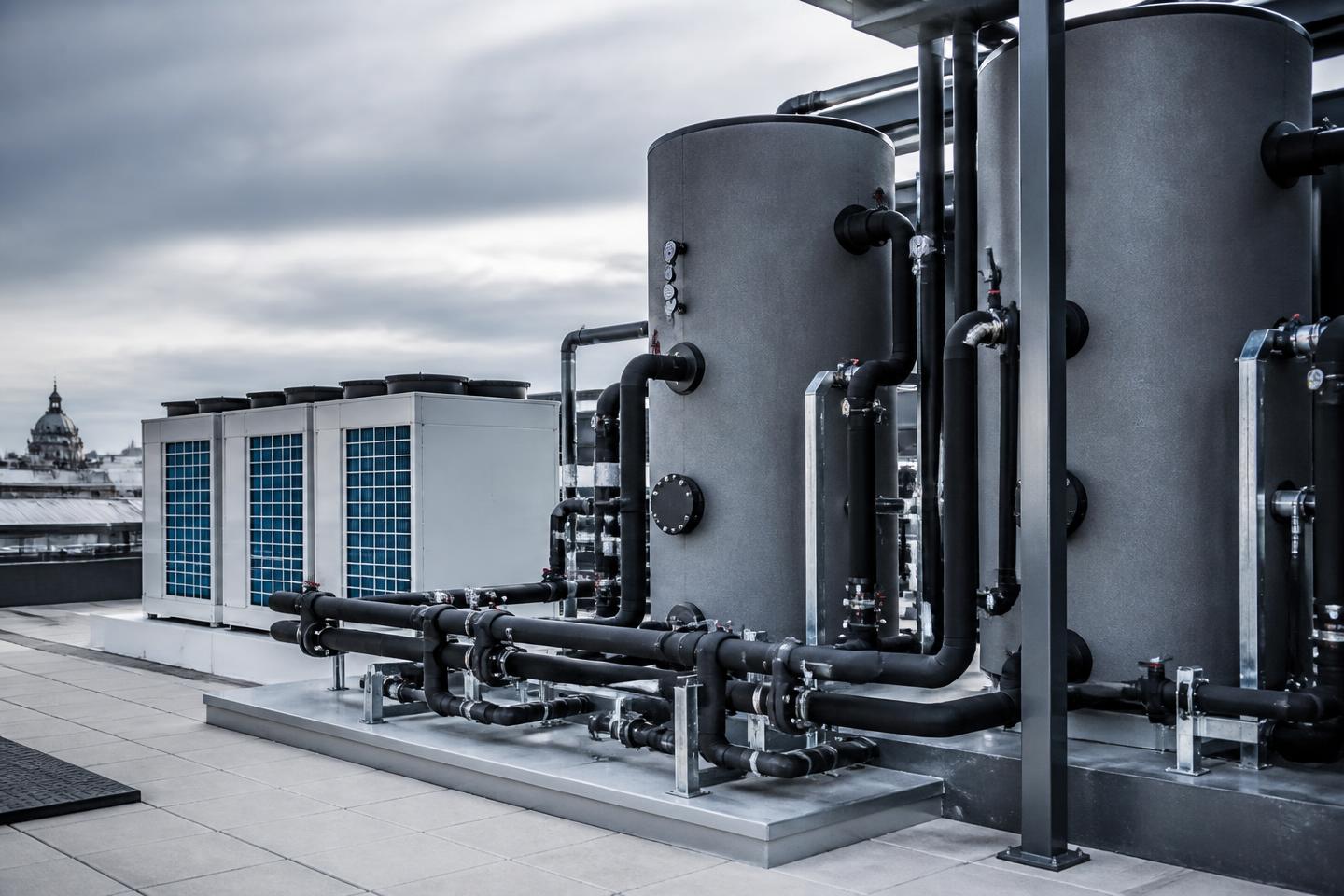 Commercial hot water heat pump installation with storage tanks on a building rooftop